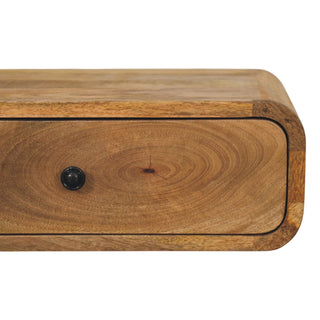 Close-up of the nightstand drawer front, showing the circular wood grain and the dark metal pull.