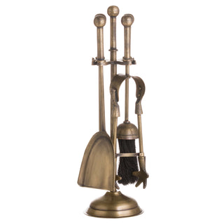 Antique brass fireplace companion set with shovel, brush, and tongs displayed on the round base.