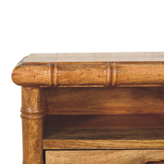 Close-up of the amber oak finish showing the carved bamboo-style moulding on the top edge and corner post.