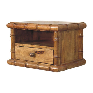 Amber oak bedside table showing open shelf, single drawer, and carved bamboo-effect frame detail.