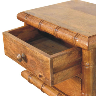 Close-up showing the top drawer of the amber oak bedside unit pulled open, revealing the internal wooden construction.