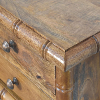 Detail showing the thick, segmented bamboo-effect moulding joint at the top corner of the amber oak bedside unit.