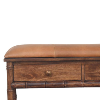 Close up showing tan cushion, wooden drawer with knob, and dark bamboo carving on the bench frame.