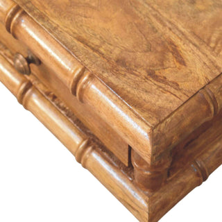 Detail of the medium brown wood finish on the console's top surface and the carved bamboo-style edge.