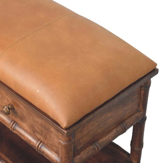 Tight detail of the tan cushioned seat and the dark wooden frame featuring bamboo carving.