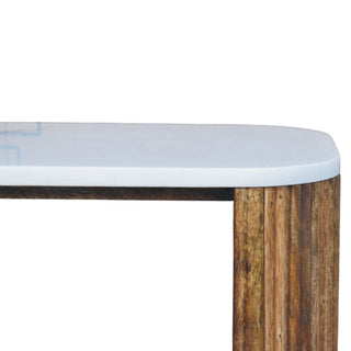 Junction detail of the rounded white marble top and the vertical reeded wood texture.