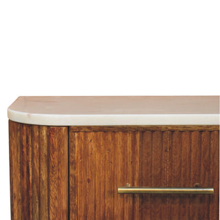 Close-up detail of the rounded corner where the white marble top meets the fluted wood cabinet.