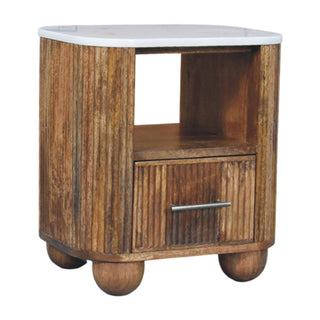 Angled view of the bedside table showing the curved reeded wood body, white marble top, and wooden bun feet.