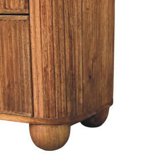 Close-up of the wooden chest showing the vertical panelling, rounded base, and chunky bun feet.