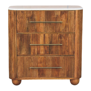 Three-drawer chest with vertical wood panelling, rounded corners, white marble top, and horizontal brass handles.