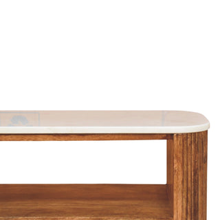 Close view of the rounded white marble top edge meeting the fluted wooden side panel of the bench.