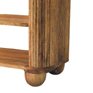 Close view of the wooden bench corner showing the fluted side, internal shelves, and rounded ball feet.