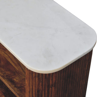 Rounded corner of the white marble top, fluted dark wood side, and visible internal wooden shelf.