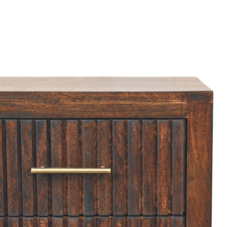 Close-up of the dark wood finish, vertical fluting texture on the drawer front, and brass bar handle.