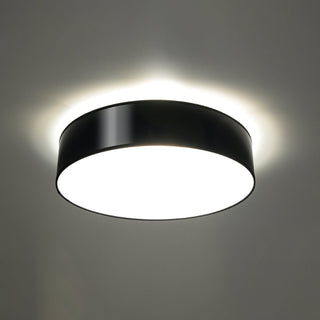 Black ceiling light fixture showing both downward illumination and an upward halo of light on the ceiling.