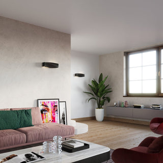 Styled living room scene showing two black ceramic SIGMA lamps mounted on light textured walls.