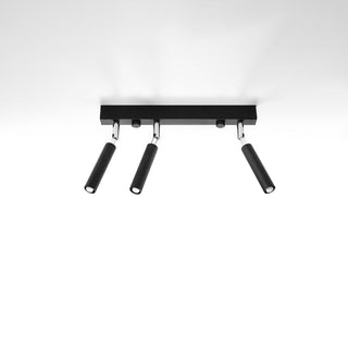Black rectangular ceiling bar with three cylindrical spotlights attached via chrome pivot joints.