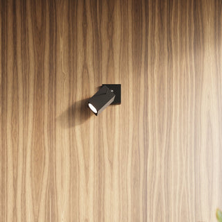 Detail of the black adjustable spot head design, illuminated and mounted on a vertical wood panel.