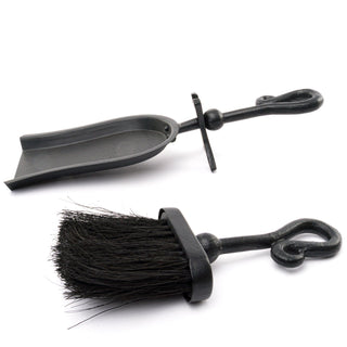 Black metal dustpan and brush components shown separately, highlighting the matte finish and forged looped handles.