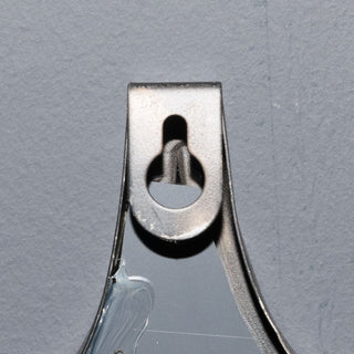 Detail of the metal keyhole bracket used for hanging the black metal wall mirror.