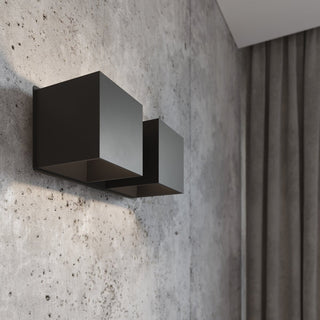 Black wall lamp fixed to a textured concrete wall, casting light downwards, adjacent to a grey curtain.