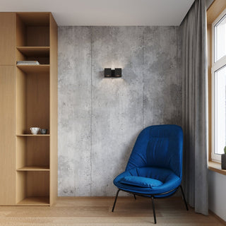 Black wall lamp mounted on a concrete wall between light oak shelving and a modern blue chair.
