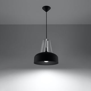 Black pendant lamp hanging, illuminated bulb casting a bright pool of light onto a grey surface.