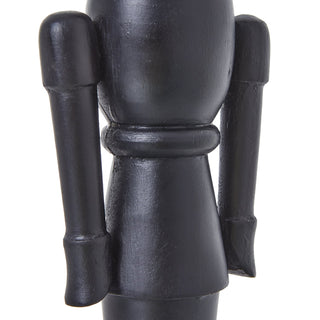 Detail shot of the black wooden nutcracker's body, showing the painted wood texture and separate arms.