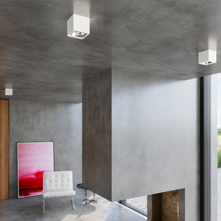 Three white lamps on a concrete ceiling, illuminating a modern interior with a large structural pillar.