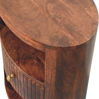 Angled close-up of the bedside table showing the curved top and the fluted drawer with a brass knob.