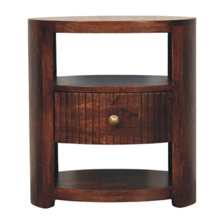 Front-on view of dark wood bedside table with open storage and a single drawer featuring vertical fluting.