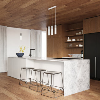 Three-light pendant positioned over a white marble kitchen island, with the single light pendant to the left.