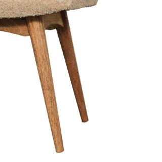 Close-up of two angled wooden legs showing the grain, supporting the cream boucle seat structure above.