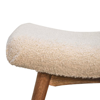 Tight close-up showing the fluffy texture of the cream boucle upholstery on the rounded seat edge.