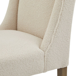 Cream bouclé fabric close-up showing the seam where the seat meets the side of the chair.