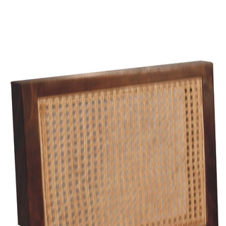 Close up of the dark wood frame corner and the vertical weave of the rattan backrest.