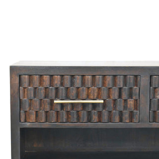 Dark wood drawer detail showing the repeating carved block pattern and the slim brass pull handle.