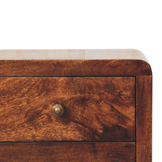 Rich wood grain detail on the top drawer of the bedside cabinet, showing the rounded corner and small metal knob.