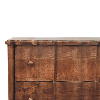 Detail shot of the dark wood chest showing the top edge profile, brass handle, and fluted drawer fronts.