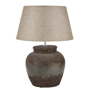 Plain front-on view of the ceramic table lamp with an aged, mottled brown base and a beige fabric shade.