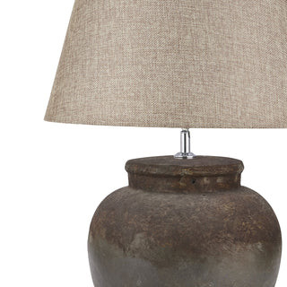 Close-up of the textured brown ceramic base, chrome fitting, and beige fabric shade.