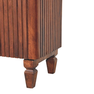 Close-up of the cabinet's bottom corner showing vertical fluting and two turned, tapered wooden feet.