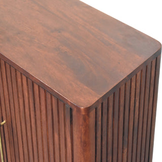 Detail of smooth dark wood top surface meeting the vertically fluted cabinet side.