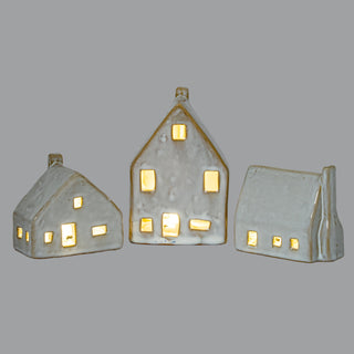 Front view of three ceramic cottages with LED lights glowing warmly through the window openings.