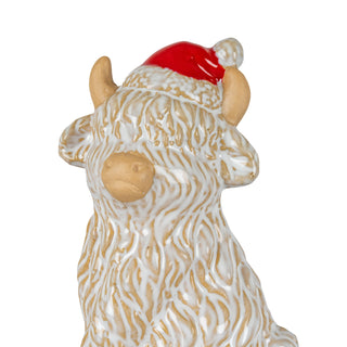 Close detail of the ceramic cow's head and body, showing the textured white glaze and the red Santa hat.