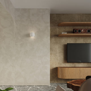 Wall light fixture illuminating a pale stucco wall next to a media console and wooden shelving.