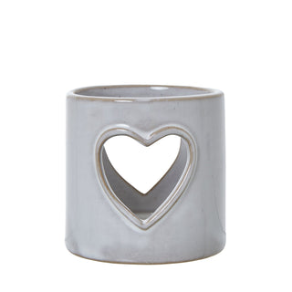 Cylindrical white ceramic tealight holder with a large heart shape cut out on the front.
