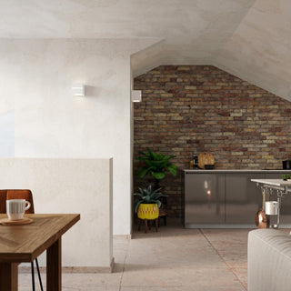 Two ceramic lamps lighting a textured white wall and a corner leading to an exposed brick kitchen area.