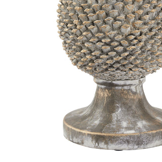 Close-up of the ceramic pinecone ornament's pedestal base, showing distressed grey finish and gold accents.