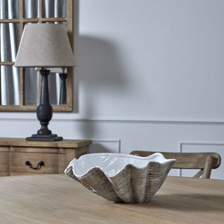 Textured shell planter on a wooden surface, angled towards a dark lamp, rustic mirror, and panelled grey wall.